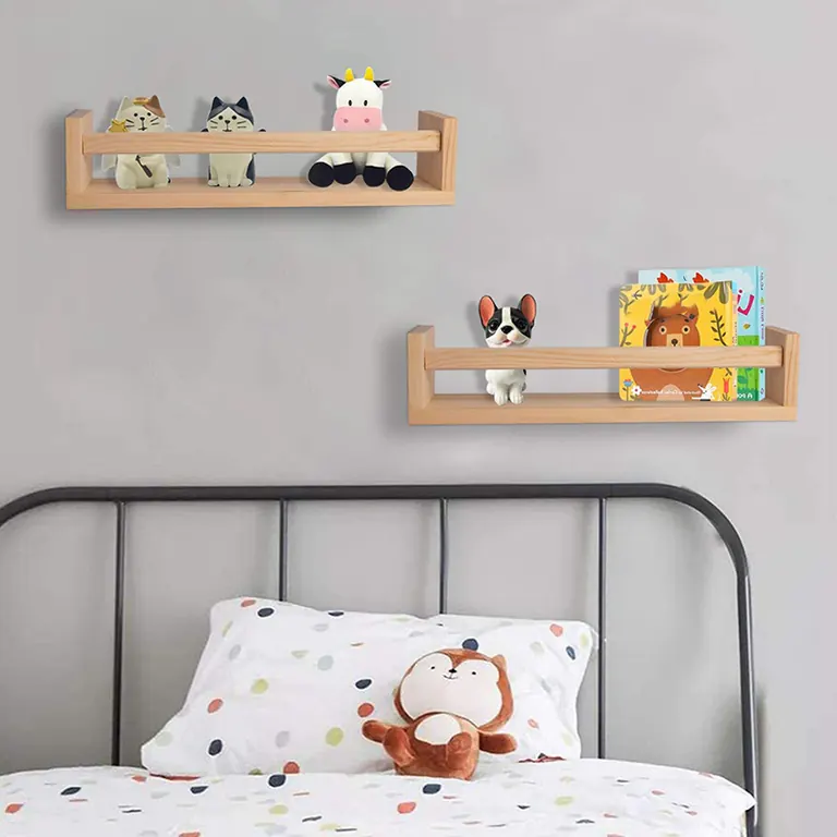 Two natural wood wall shelves above a bed, holding small figures and children's books