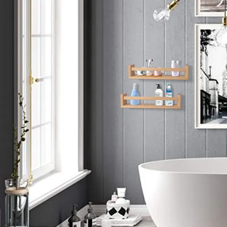 Two natural wood wall shelves holding bottles on a grey bathroom wall beside a window