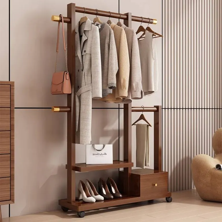 Dark wood clothes rack holding clothes and shoes, seen at an angle in a bedroom